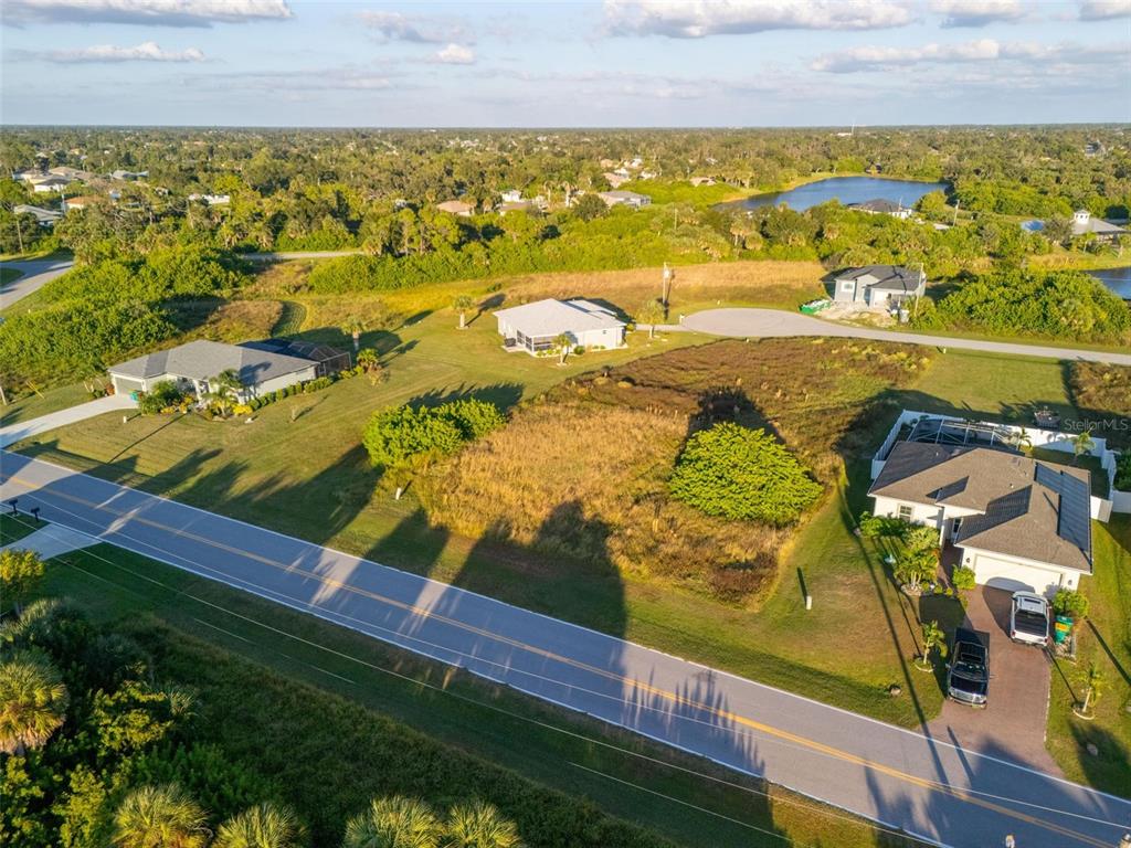 An aerial view shows a vacant lot situated between two houses along a paved road — 278 INDIAN CREEK DRIVE, ROTONDA WEST, FL