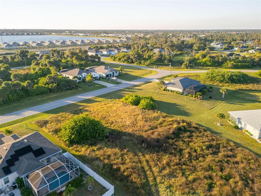 An aerial view shows a vacant, grassy lot situated between several suburban houses and roads — 278 INDIAN CREEK DRIVE, ROTONDA WEST, FL