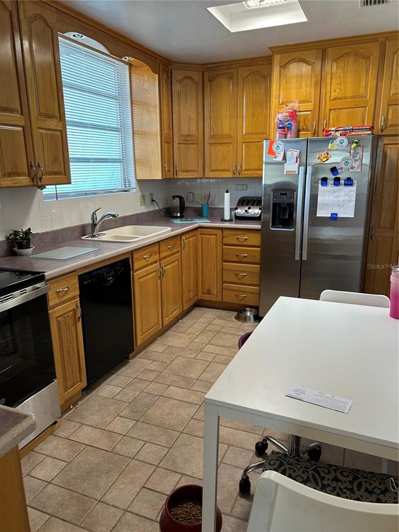 A kitchen features light wood cabinets, a stainless steel refrigerator, and a white dining table — 2201 S PENINSULA DRIVE, DAYTONA BEACH, FL