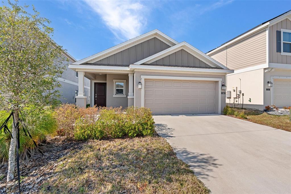 A single-story suburban house features a beige exterior, a two-car garage, and a front porch — 360 LOCH CT, DAVENPORT, FL