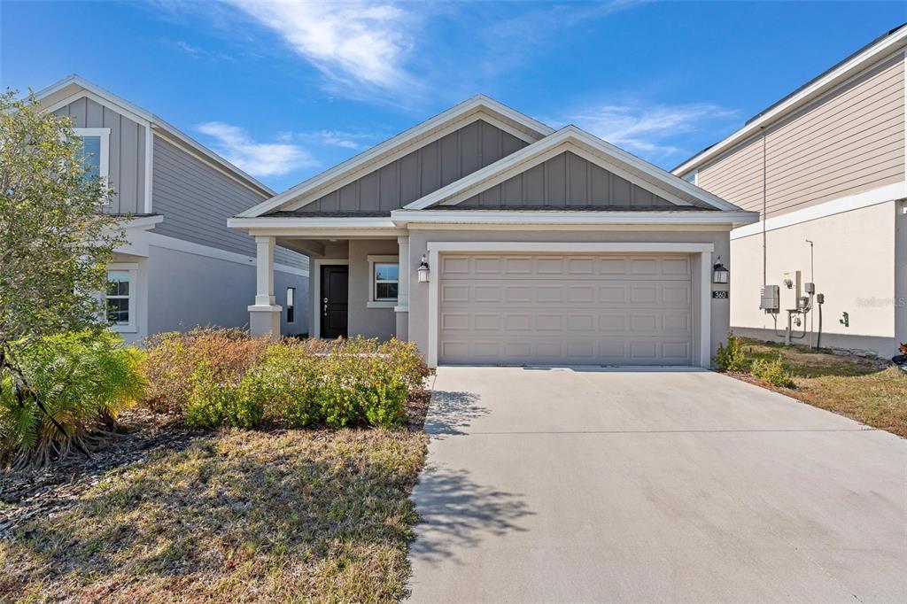 A single-story suburban house with a two-car garage, gray siding, and a concrete driveway — 360 LOCH CT, DAVENPORT, FL