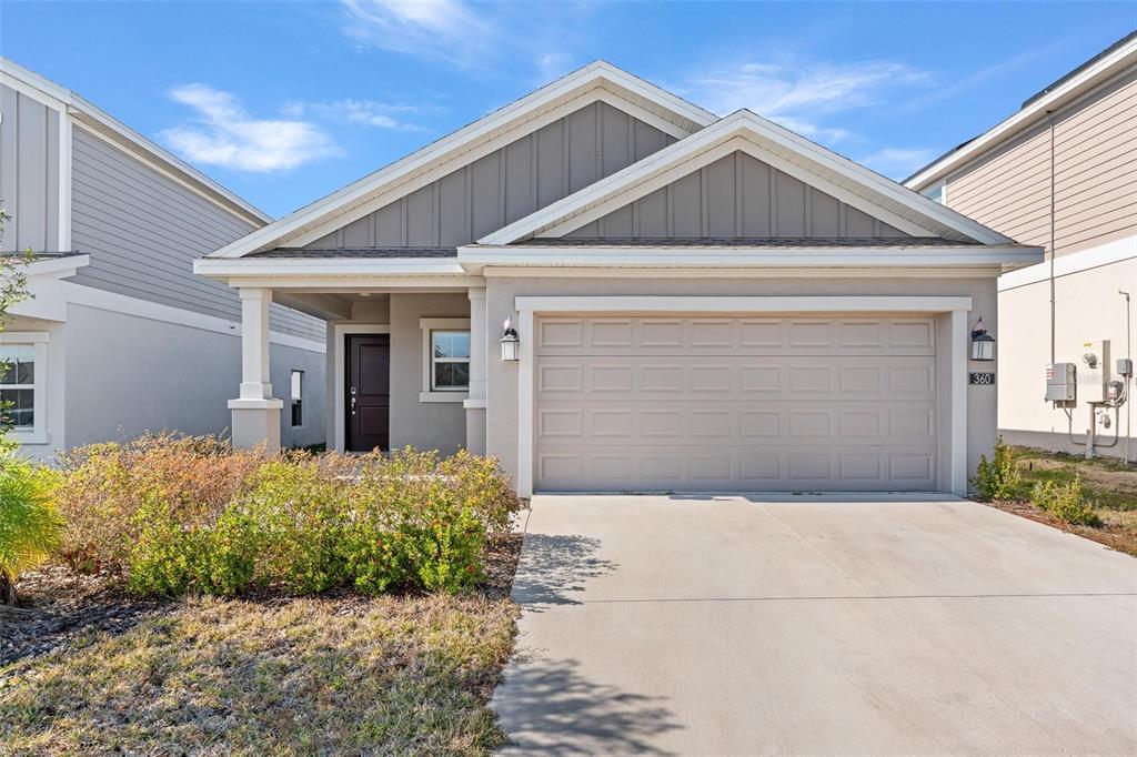 A single-story house with a beige stucco facade, a two-car garage, and a covered entryway — 360 LOCH CT, DAVENPORT, FL