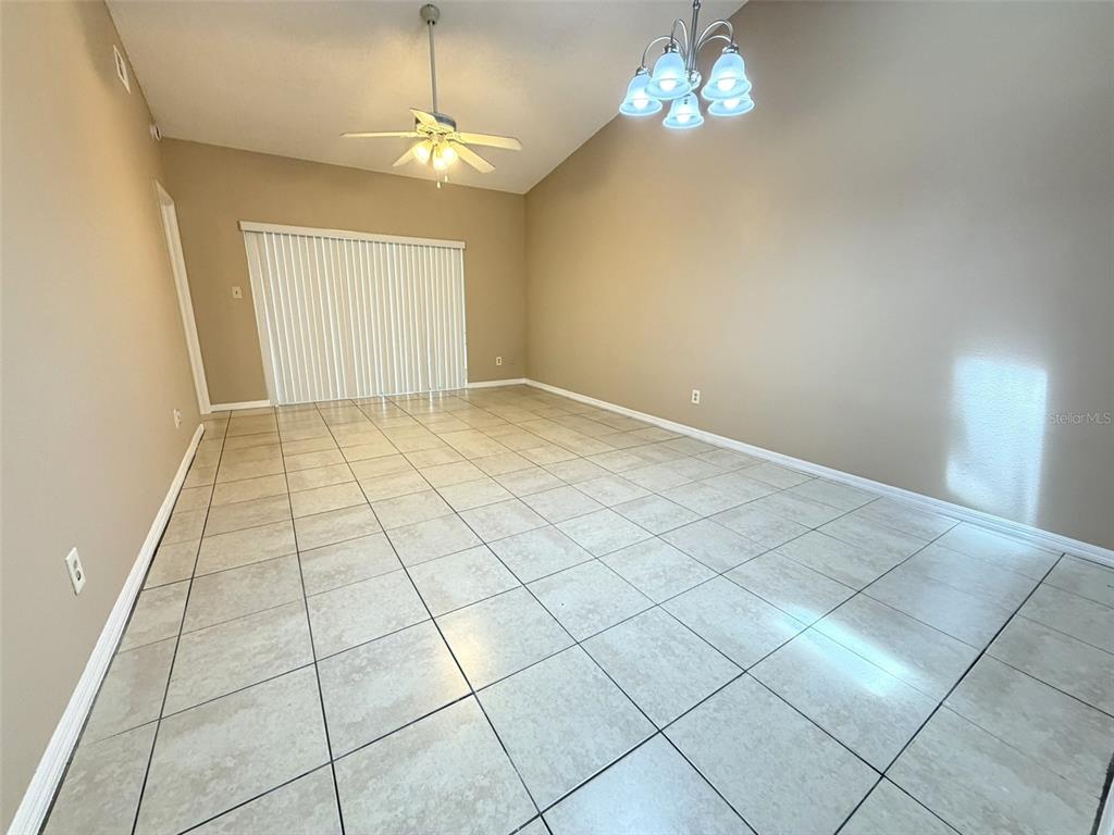 An empty room with beige walls, tile flooring, a ceiling fan, and a chandelier — 7916 RICHWOOD DRIVE, ORLANDO, FL
