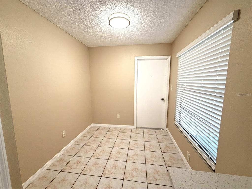 A small room with beige walls, tile flooring, a white door, and a window with blinds — 7916 RICHWOOD DRIVE, ORLANDO, FL