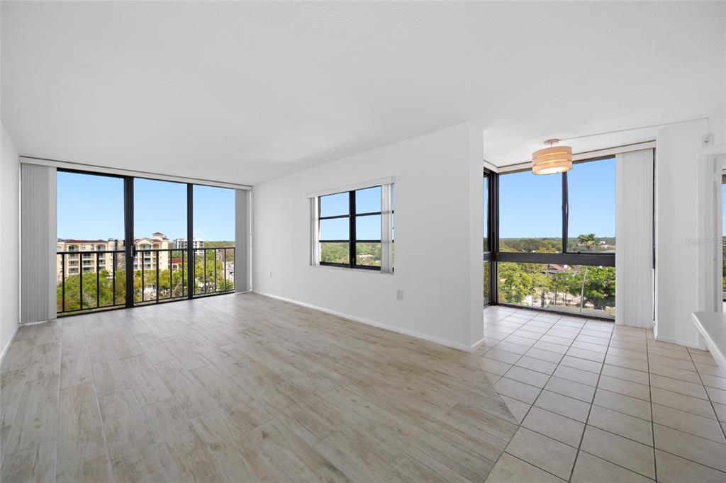 An open living area features light wood-look tile, white walls, and floor-to-ceiling windows — 500 N OSCEOLA AVENUE UNIT 810, CLEARWATER, FL