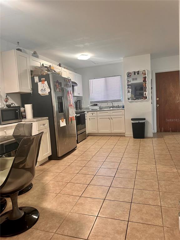 A kitchen features white cabinets, stainless steel appliances, and light-colored tile flooring — 2938 CLARK ROAD UNIT 102, SARASOTA, FL