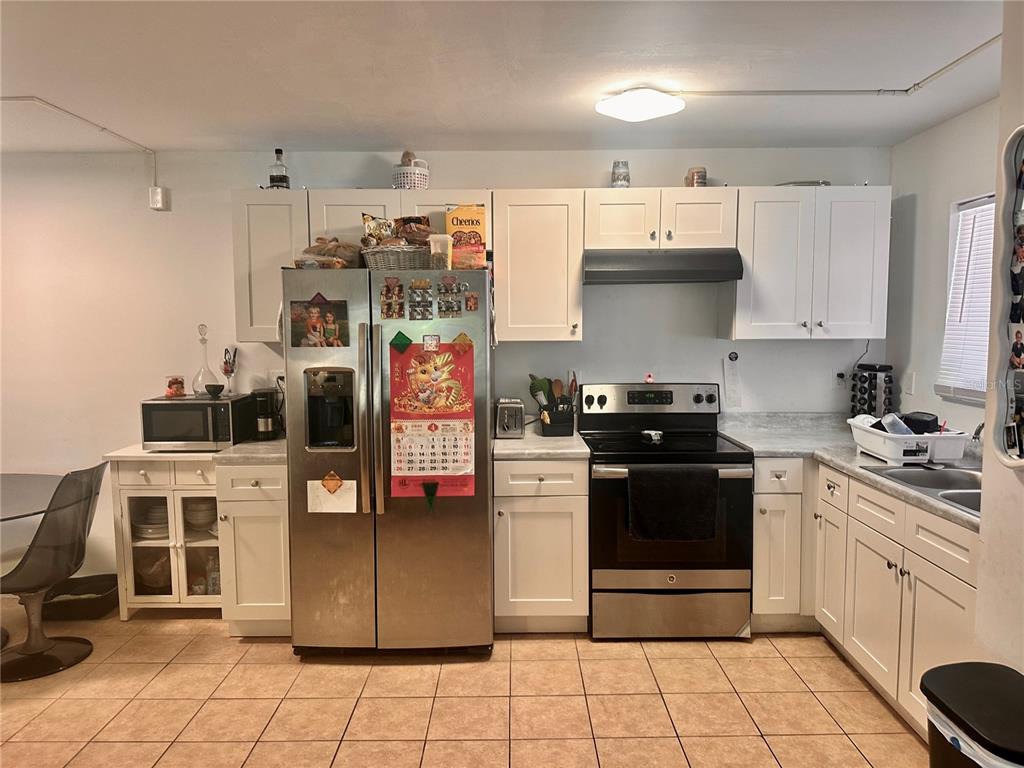 A kitchen with white cabinets, stainless steel appliances, and tile flooring — 2938 CLARK ROAD UNIT 102, SARASOTA, FL