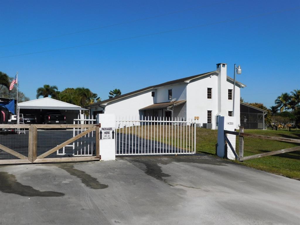 A white house with a metal gate and a detached carport under a clear sky — 14201 SW 48th Court, Miramar FL 33027, MIRAMAR, FL