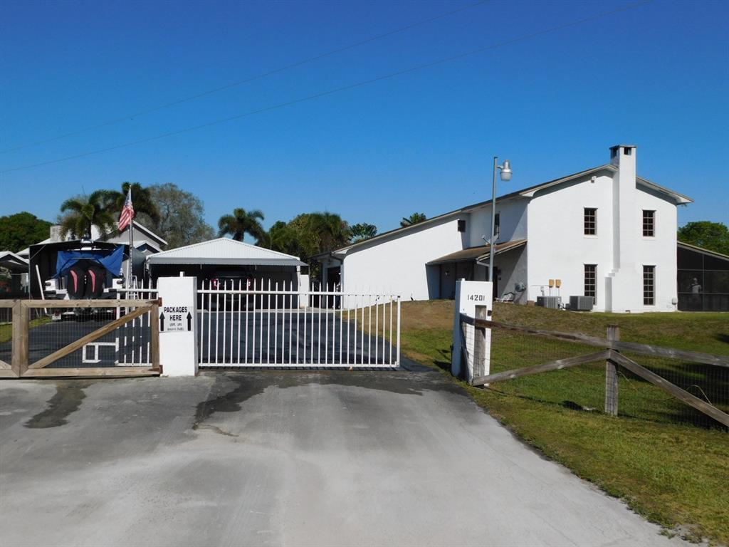 A white house with a chimney and a gated driveway featuring a covered parking area — 14201 SW 48th Court, Miramar FL 33027, MIRAMAR, FL