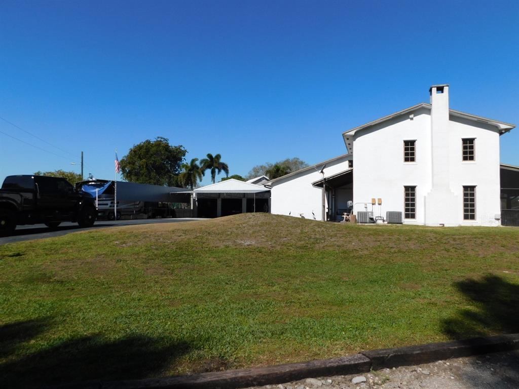 A white two-story house with a chimney stands next to a large metal carport — 14201 SW 48th Court, Miramar FL 33027, MIRAMAR, FL