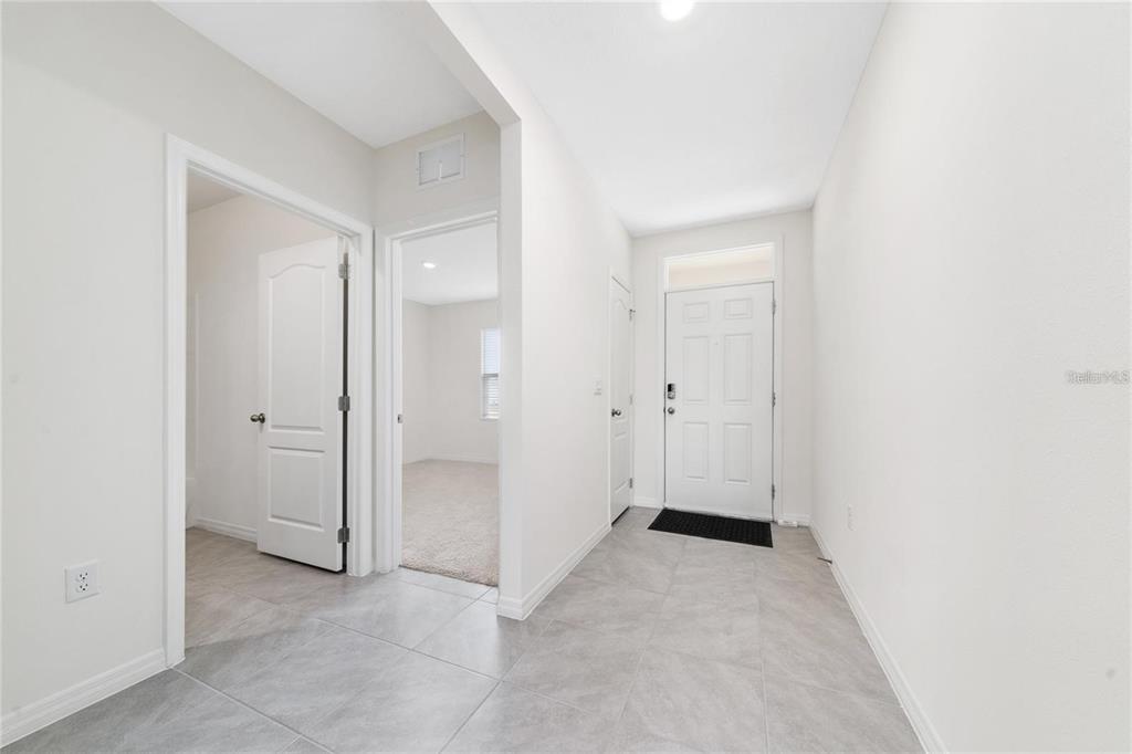 A bright entryway features light gray tile flooring, white walls, and two interior doorways — 1213 RED HILL ROAD, DAVENPORT, FL