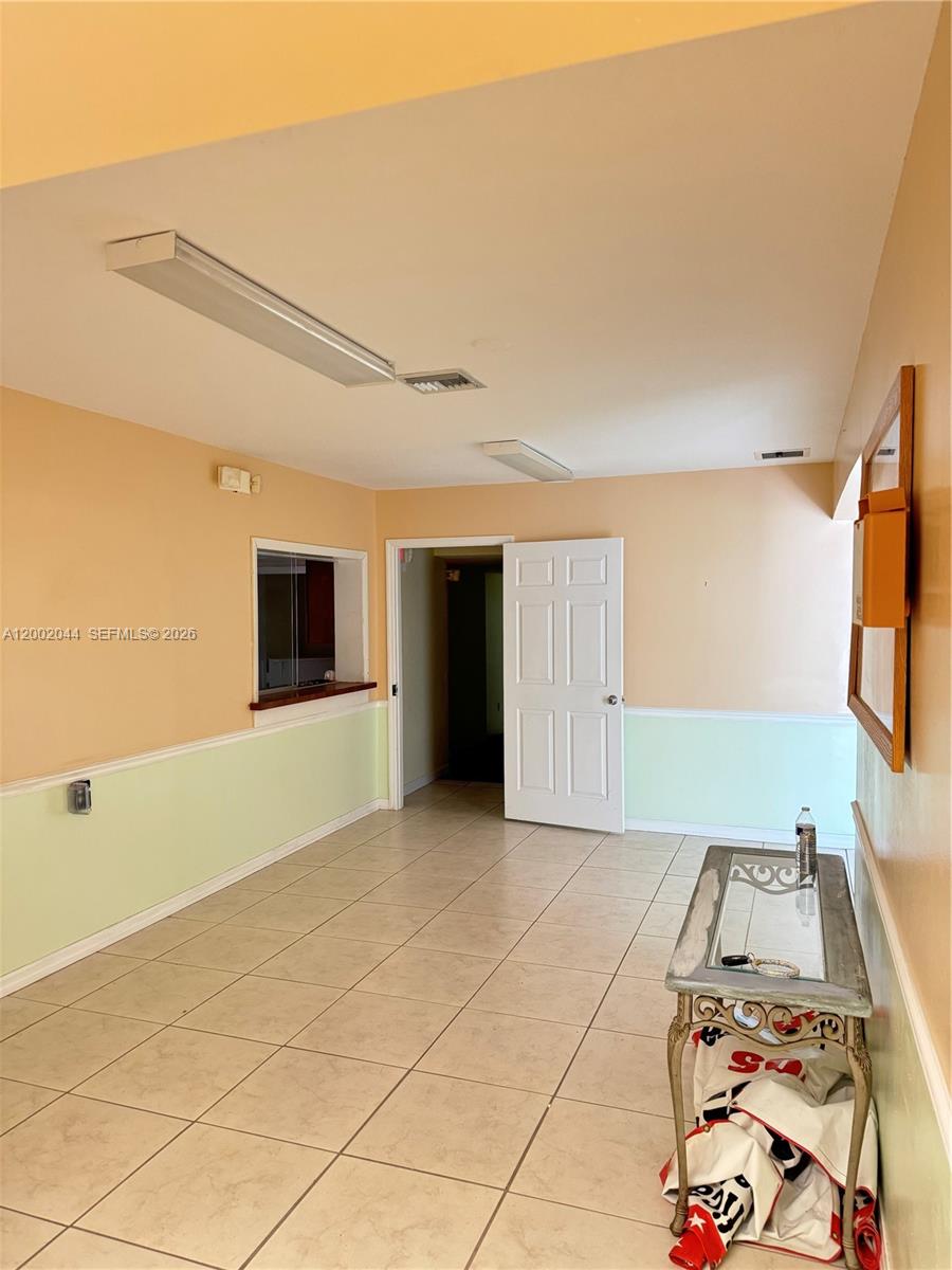 A room with beige and light green walls, tile flooring, and a white door — 706 N 7th St, Fort Pierce FL 34950, FORT PIERCE, FL