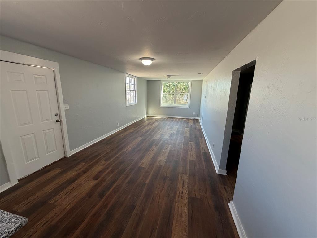An empty room with gray walls, dark wood-look flooring, and two windows — 325 S FRANKLIN STREET, DAYTONA BEACH, FL