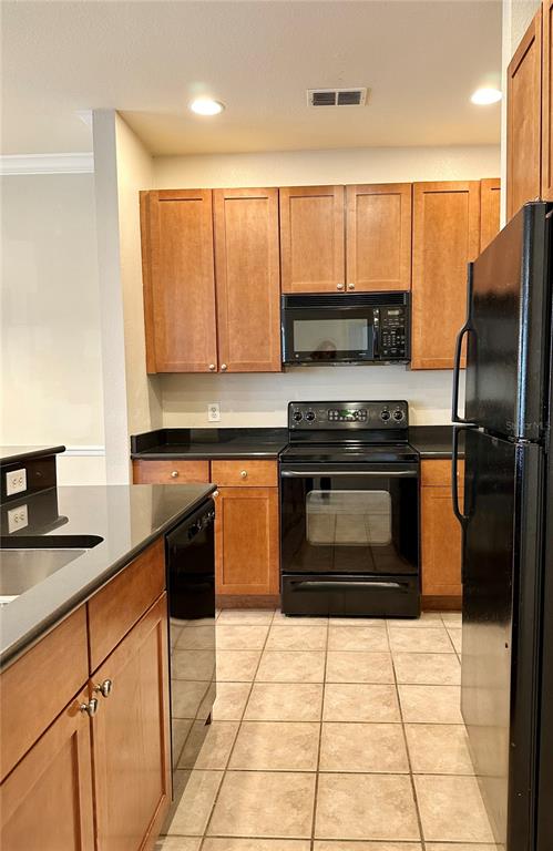 A kitchen features wood cabinets, black appliances, and tile flooring — 2249 PORTOFINO PLACE UNIT 2221, PALM HARBOR, FL
