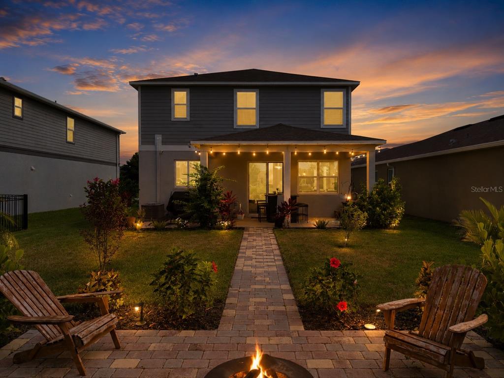 A backyard view of a two-story house with a patio, fire pit, and string lights — 11567 GALLATIN TRAIL, PARRISH, FL