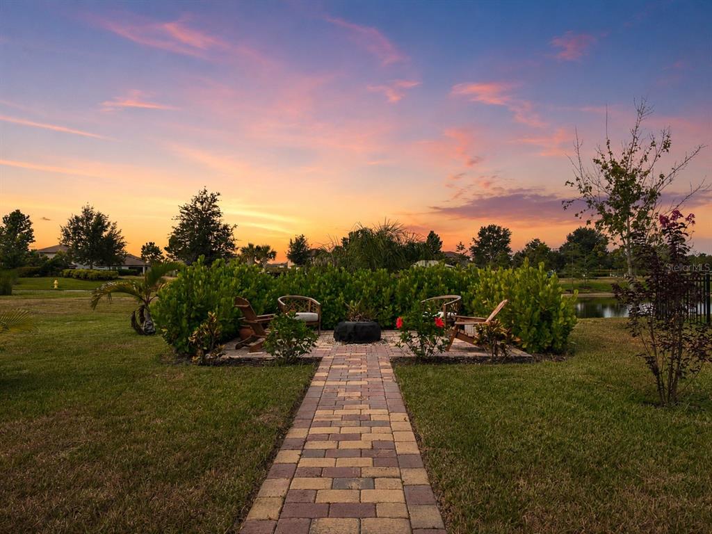 A brick walkway leads to a patio with chairs and a fire pit at sunset — 11567 GALLATIN TRAIL, PARRISH, FL