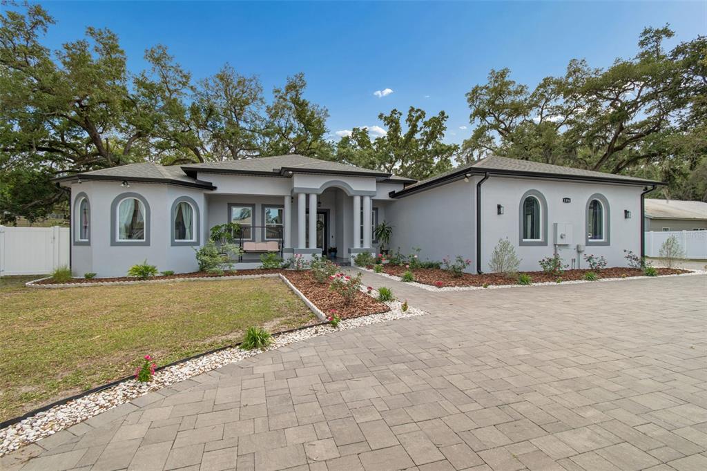 A single-story house with a gray stucco exterior, arched windows, and a paved driveway — 106 W 122ND AVENUE, TAMPA, FL