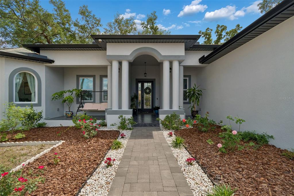 A paved walkway leads to the arched, columned entryway of a gray stucco house — 106 W 122ND AVENUE, TAMPA, FL