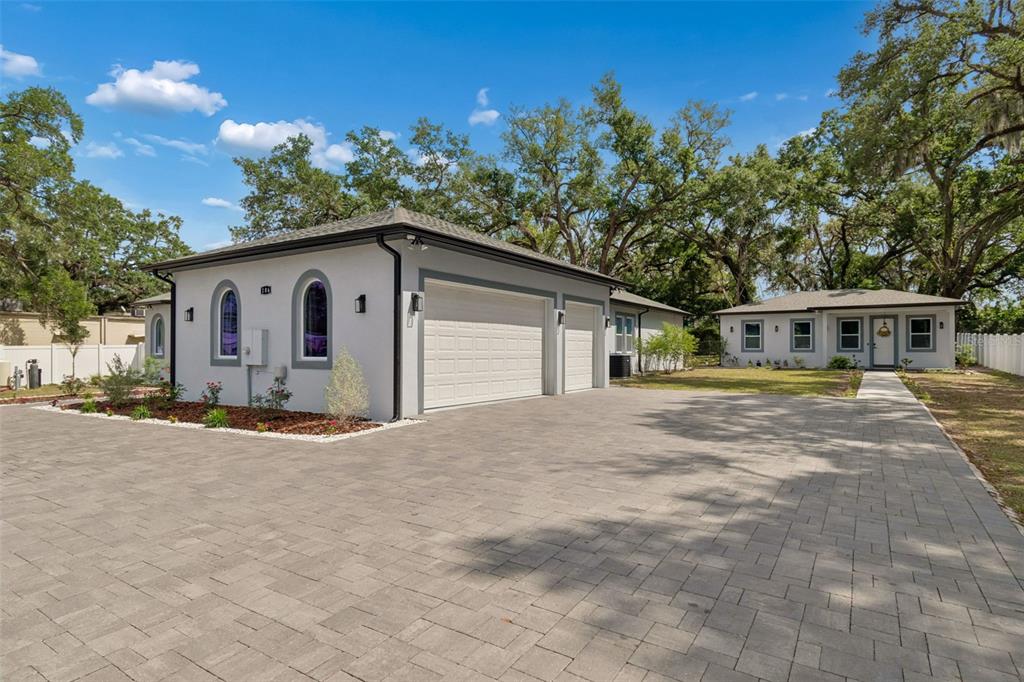 A detached two-car garage with a paved driveway sits in front of a single-story house — 106 W 122ND AVENUE, TAMPA, FL