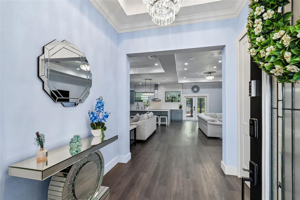 A foyer with a mirrored console table leads into an open-concept living room and kitchen — 106 W 122ND AVENUE, TAMPA, FL