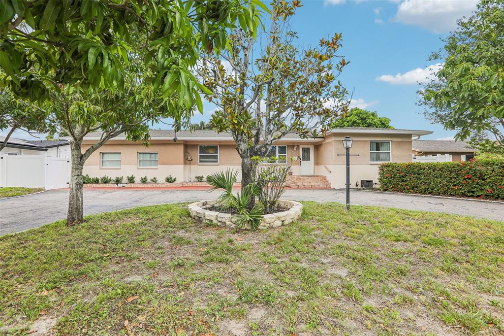 A single-story house with a beige facade, a circular driveway, and a central landscaped tree — 2709 49TH STREET N, ST PETERSBURG, FL