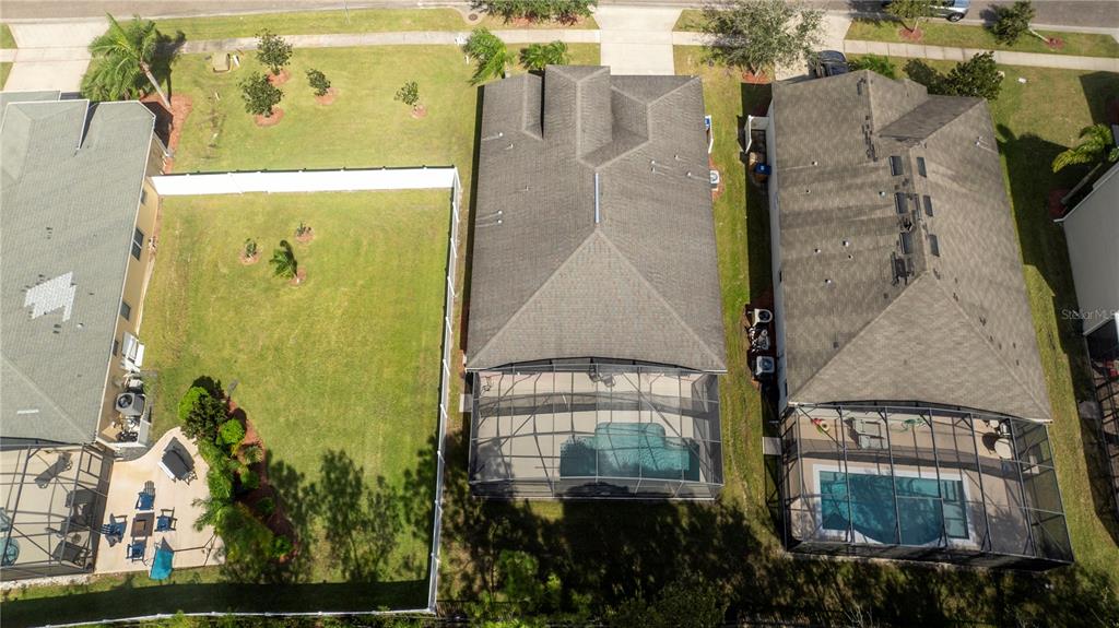 An aerial view shows three suburban houses with swimming pools and fenced backyards — 4724 BLUE DIAMOND STREET, KISSIMMEE, FL