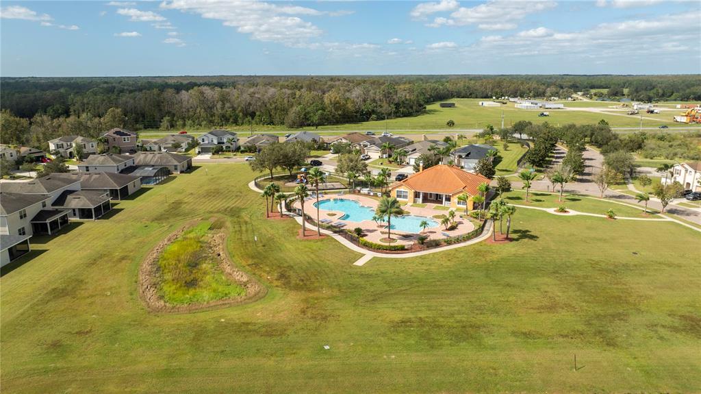 An aerial view shows a community pool and clubhouse surrounded by houses and green space — 4724 BLUE DIAMOND STREET, KISSIMMEE, FL