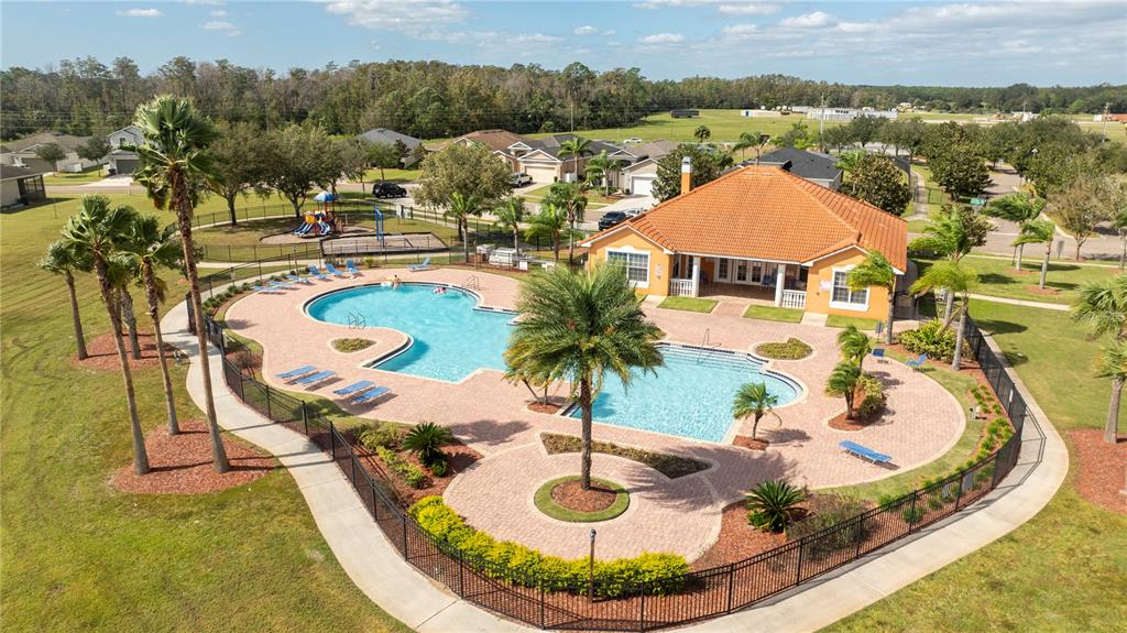 An aerial view shows a community swimming pool and clubhouse surrounded by a fenced patio — 4724 BLUE DIAMOND STREET, KISSIMMEE, FL
