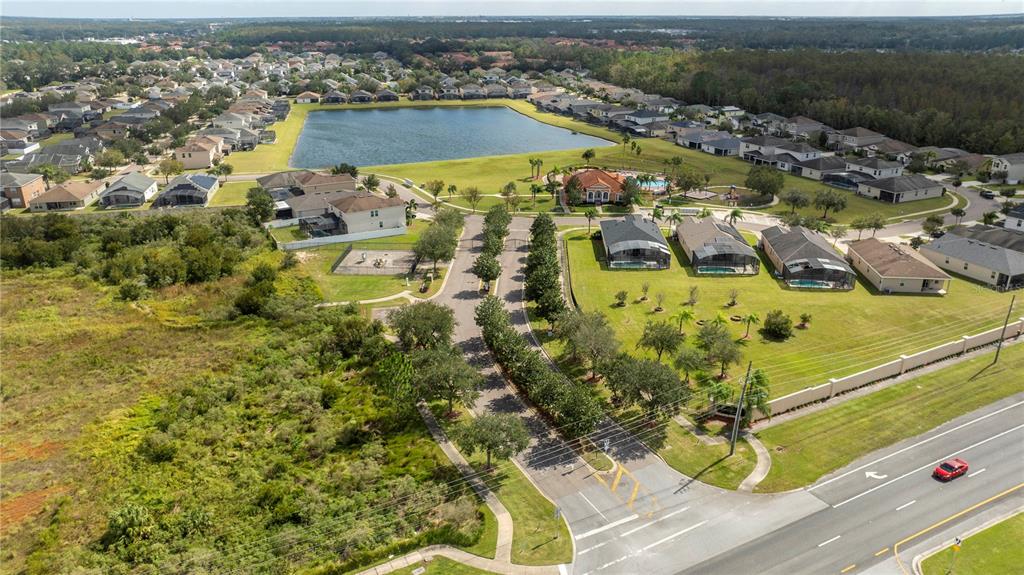 An aerial view shows a suburban neighborhood with a lake, community pool, and nearby road — 4724 BLUE DIAMOND STREET, KISSIMMEE, FL