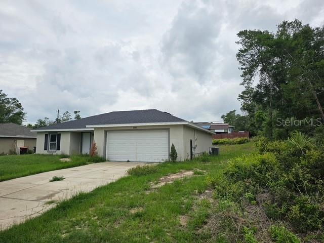 This single-story house features a light-colored exterior, a two-car garage, and a concrete driveway — 2292 SW 168TH LOOP, OCALA, FL
