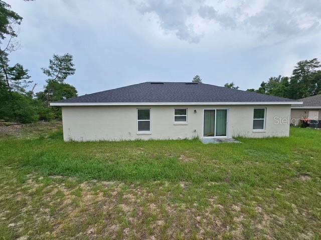 The rear exterior of a single-story house features a light-colored stucco finish and sliding doors — 2292 SW 168TH LOOP, OCALA, FL