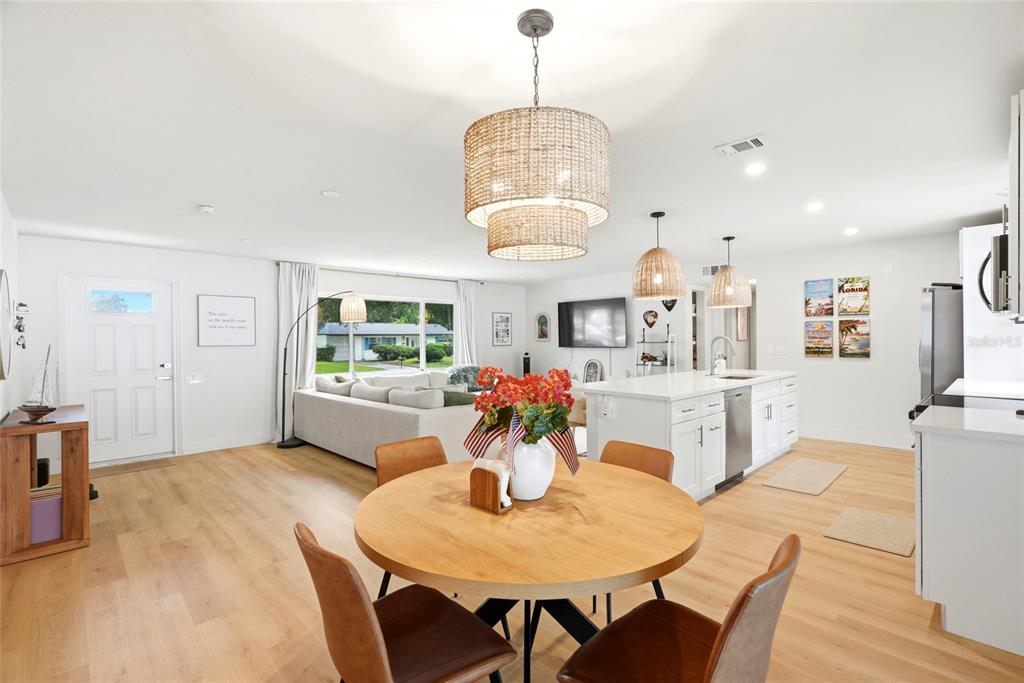 An open-concept living and dining area features light wood flooring, a kitchen island, and pendant lighting — 11500 70TH TERRACE, SEMINOLE, FL