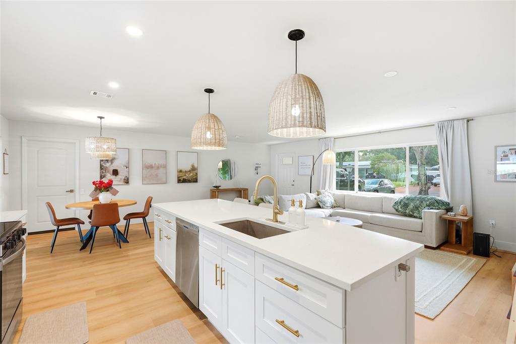 A bright open-concept kitchen and living area features a white island, wood floors, and pendants — 11500 70TH TERRACE, SEMINOLE, FL