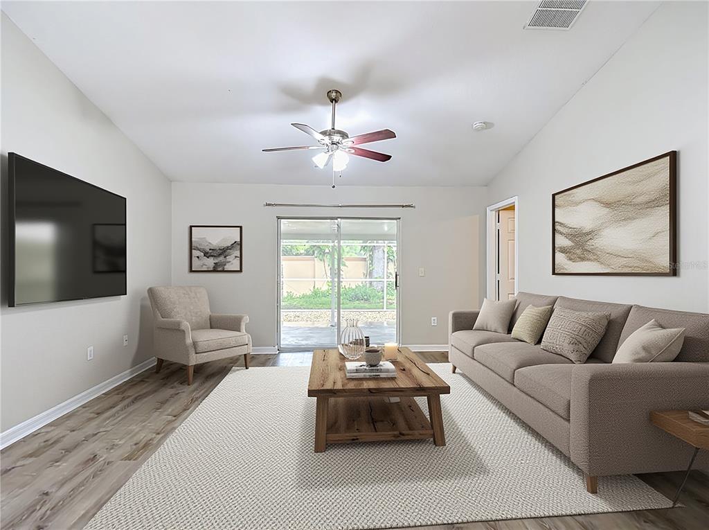 A living room features a sofa, armchair, coffee table, television, and sliding glass doors — 1129 CONCH COURT, WESLEY CHAPEL, FL