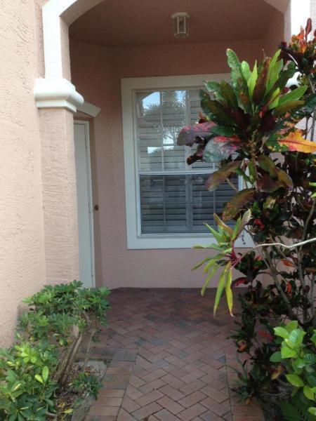 A covered entryway features a brick paver floor, a window with shutters, and potted plants — 8432 Cargill Point, West Palm Beach FL 33411, WEST PALM BEACH, FL