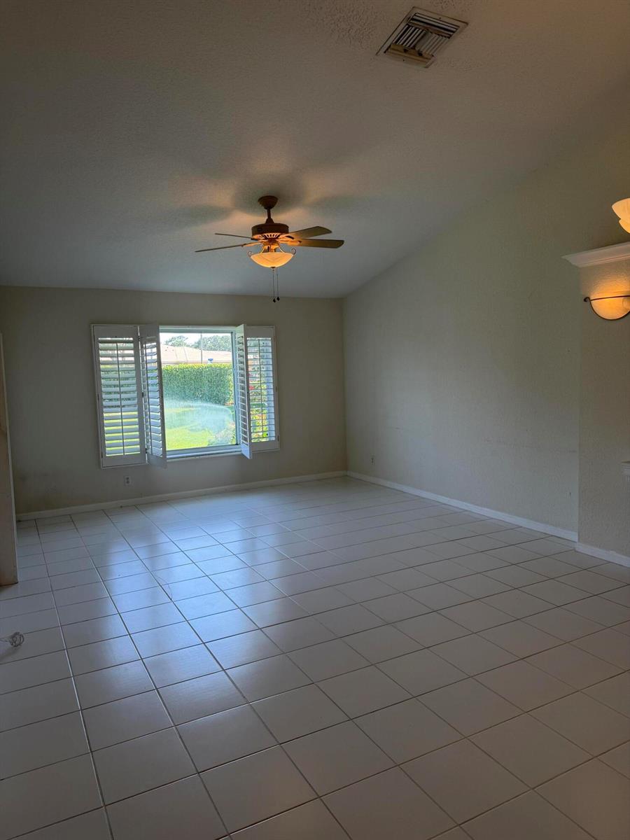 A spacious living room features white tile flooring, a ceiling fan, and plantation shutters — 8432 Cargill Point, West Palm Beach FL 33411, WEST PALM BEACH, FL