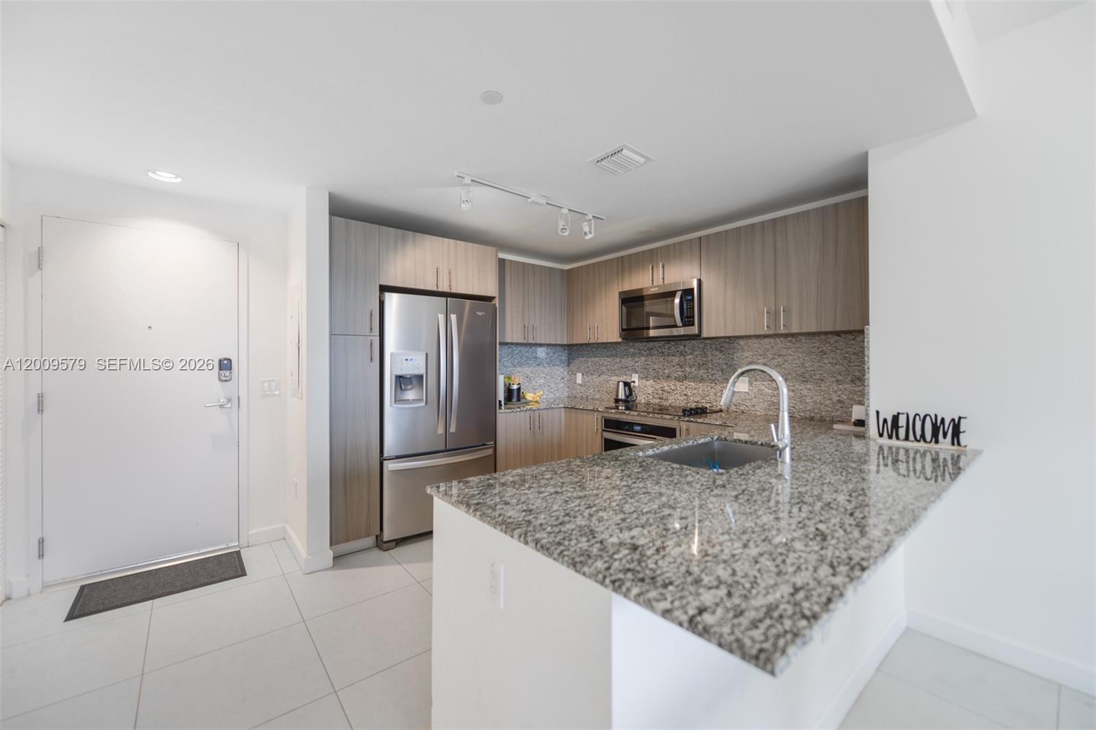 A modern kitchen features granite countertops, stainless steel appliances, and light wood cabinetry — 5350 NW 84th Ave # 509, Doral FL 33166, DORAL, FL