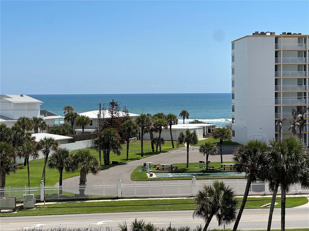An elevated view shows a coastal scene with palm trees, a parking area, and the ocean — 5300 S ATLANTIC AVENUE UNIT 3-504, NEW SMYRNA BEACH, FL