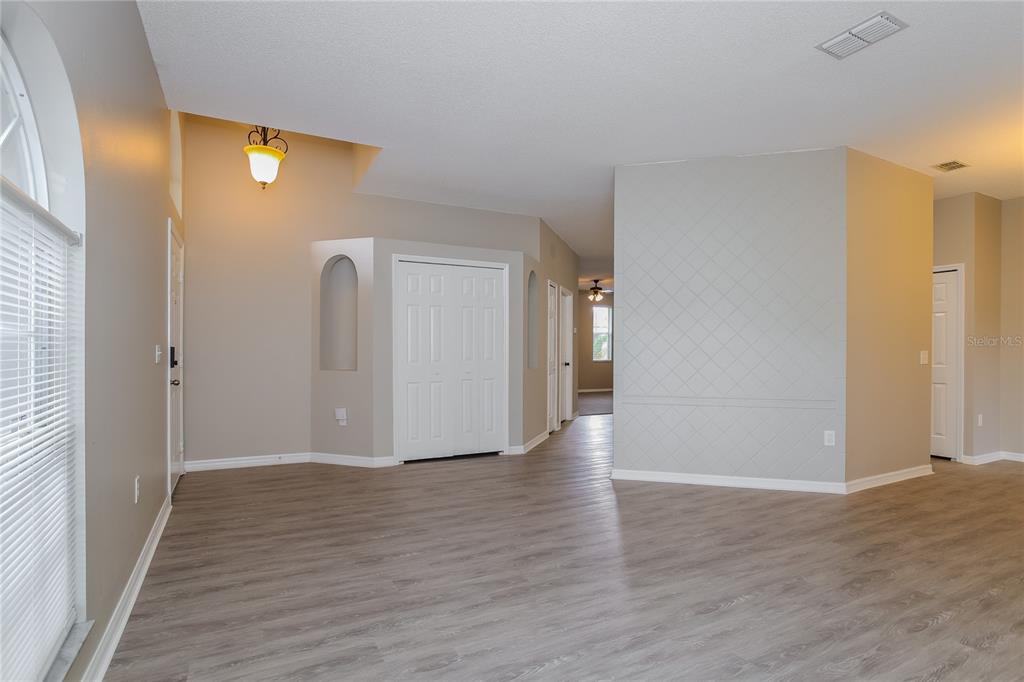 An interior view shows a living area with light-colored walls, wood-look flooring, and a closet — 421 PEPPERMILL CIRCLE, KISSIMMEE, FL