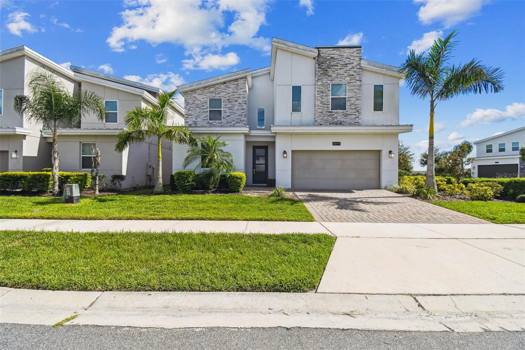 A two-story suburban house features a stone facade, a two-car garage, and palm trees — 8844 CRUDEN BAY COURT, DAVENPORT, FL