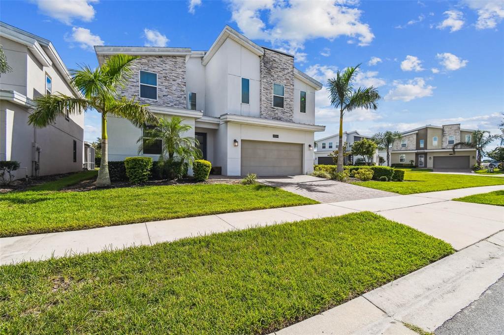 A two-story suburban house with a stone facade, a two-car garage, and palm trees — 8844 CRUDEN BAY COURT, DAVENPORT, FL