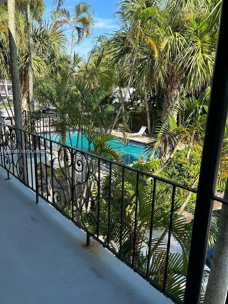 A view from a balcony overlooking a swimming pool surrounded by palm trees — 645 NE 77th St # 16, Miami FL 33138, MIAMI, FL