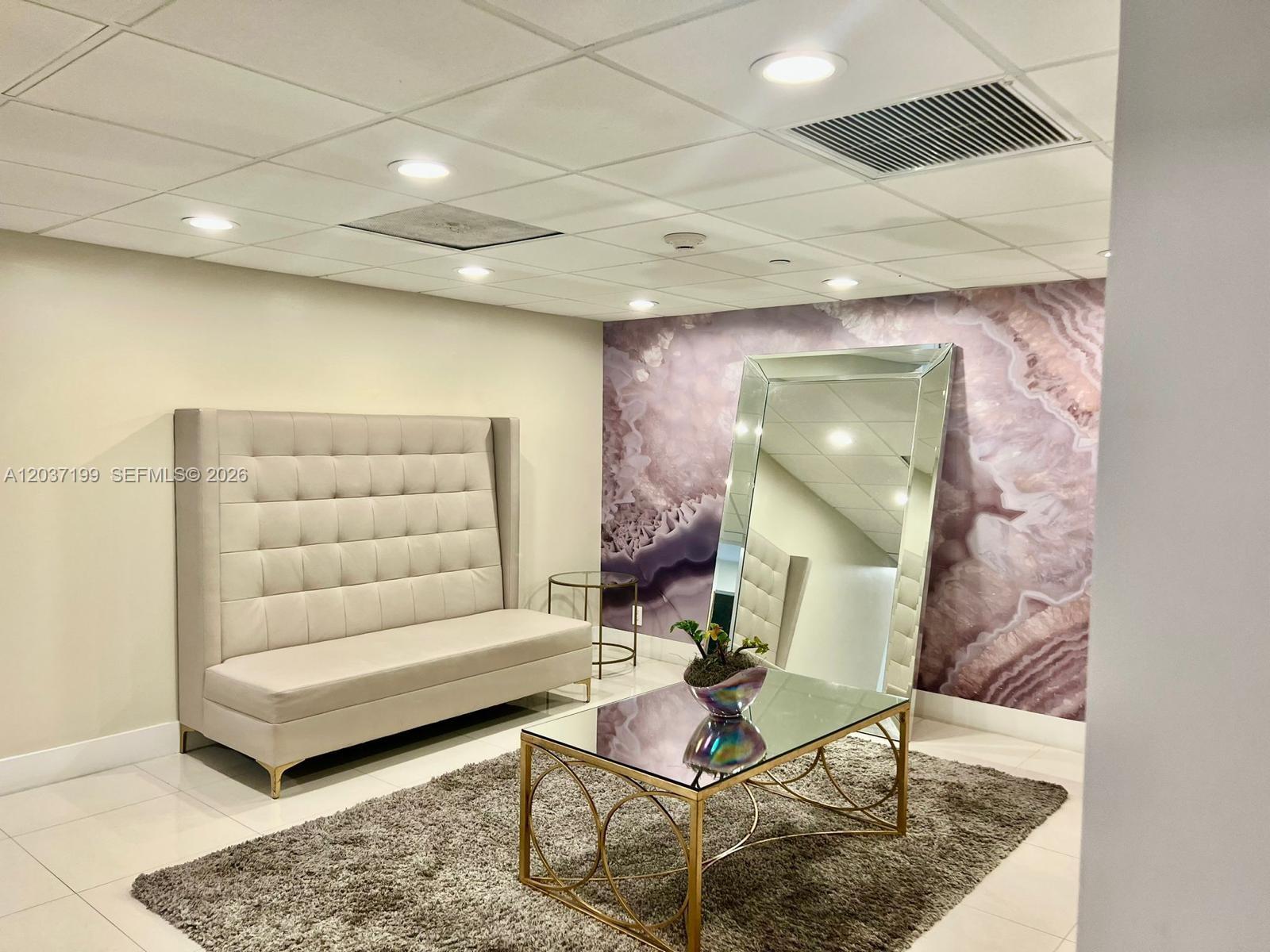 A modern lounge area features a tufted high-back sofa, a mirrored coffee table, and an accent wall — 3301 NE 5th Ave # 706, Miami FL 33137, MIAMI, FL