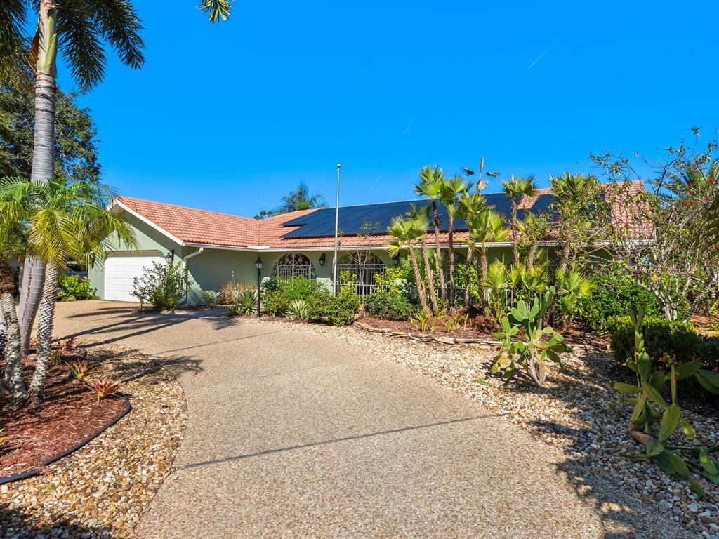 A single-story house with a tiled roof, solar panels, and a curved concrete driveway — 4725 GREENCROFT ROAD, SARASOTA, FL
