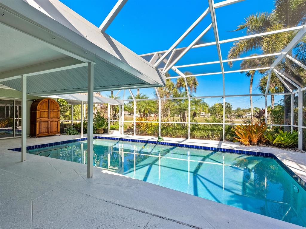 A swimming pool sits on a patio enclosed by a white metal screen cage — 4725 GREENCROFT ROAD, SARASOTA, FL