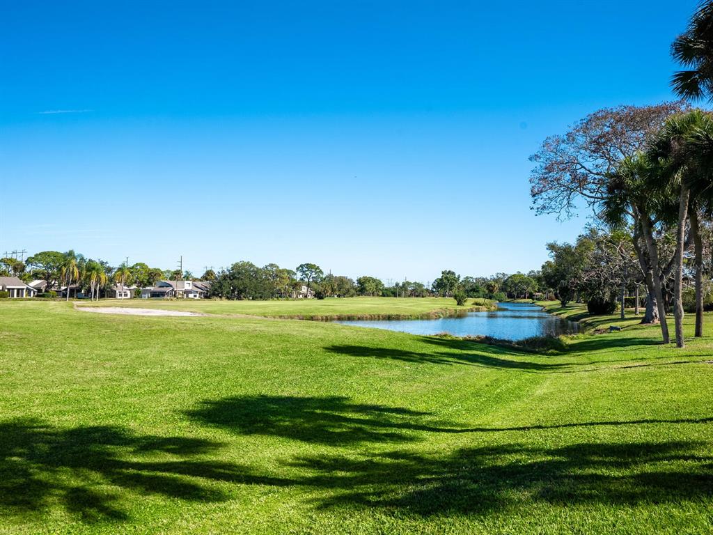 A grassy golf course fairway features a sand bunker and a pond under blue skies — 4725 GREENCROFT ROAD, SARASOTA, FL