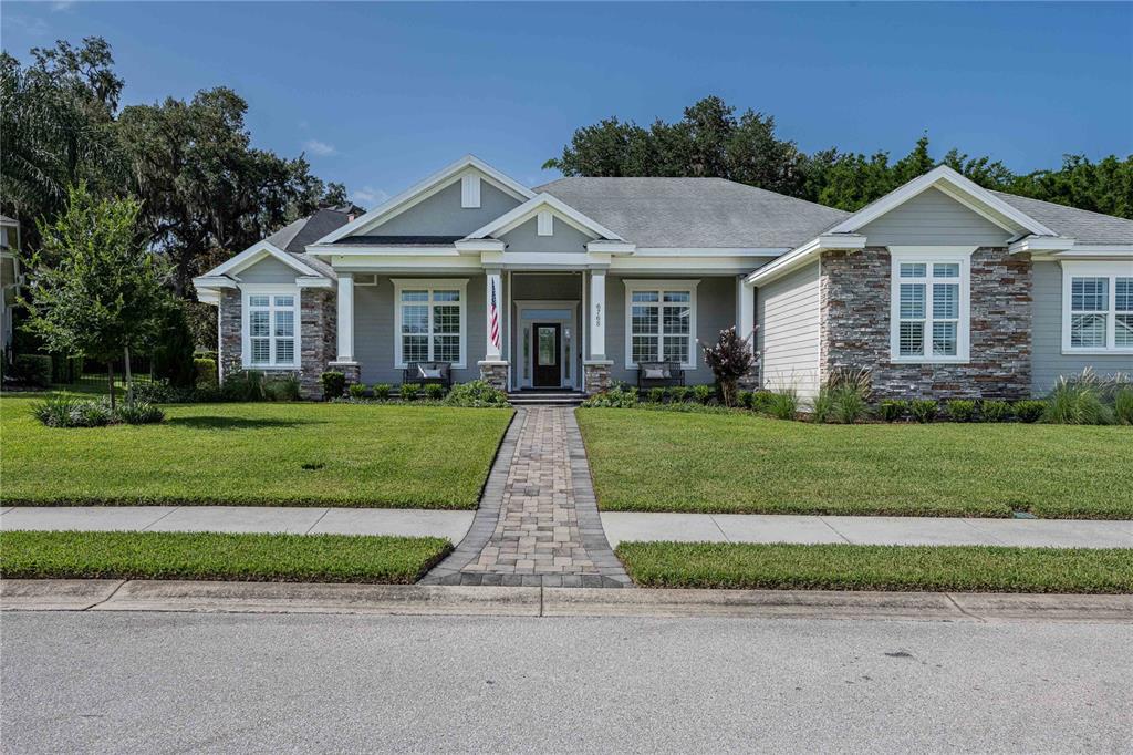 A single-story house with a stone and gray siding exterior features a paved walkway — 6768 CRESCENT WOODS CIRCLE, LAKELAND, FL