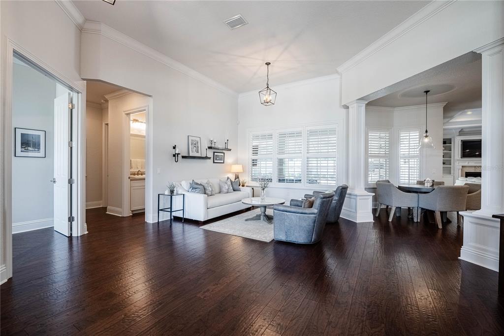 A living room with dark hardwood floors, white walls, and an adjacent dining area — 6768 CRESCENT WOODS CIRCLE, LAKELAND, FL