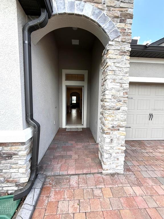 A stone-accented arched entryway leads to a front door with a view into the home — 1165 HILLTOP PLACE, ST CLOUD, FL
