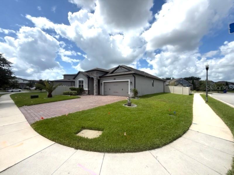 A single-story house with a paved driveway, stone accents, and a large front lawn — 1165 HILLTOP PLACE, ST CLOUD, FL